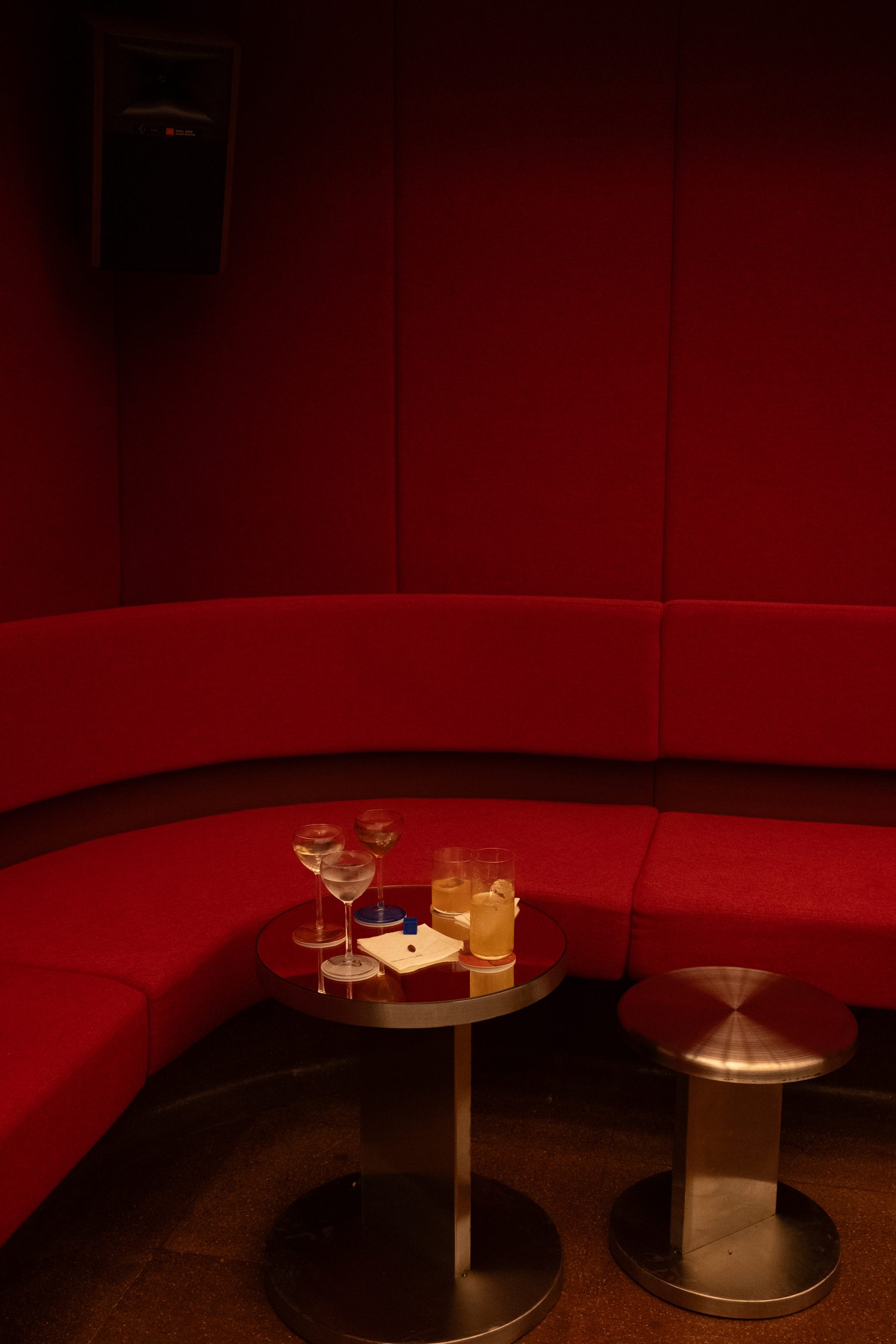 Sillón curvo rojo con mesas de cóctel en ROSSO